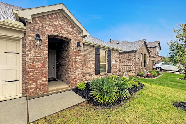 property entrance with a shingled roof, brick siding, and a lawn