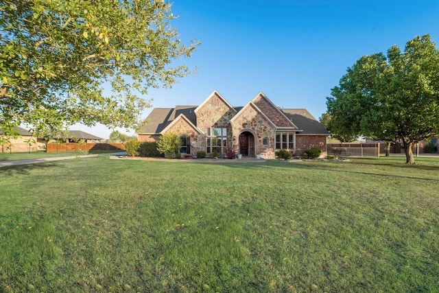 view of front of property with stone siding, fence, and a front yard