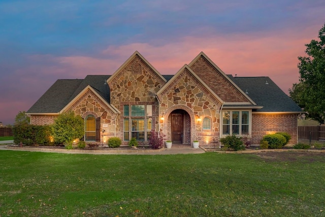 view of front of house with stone siding, brick siding, and a front lawn