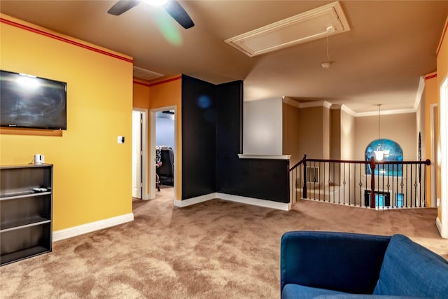 living area with ceiling fan, ornamental molding, attic access, and carpet floors
