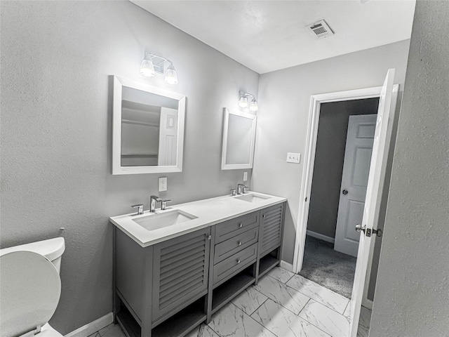 bathroom with toilet, visible vents, marble finish floor, and a sink