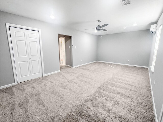 unfurnished bedroom featuring a wall unit AC, a closet, carpet floors, visible vents, and baseboards