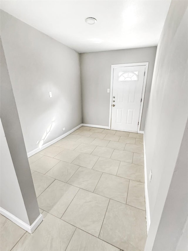 foyer entrance featuring light tile patterned flooring and baseboards