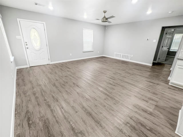 unfurnished living room featuring visible vents, wood finished floors, baseboards, and ceiling fan