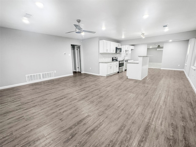 unfurnished living room featuring ceiling fan, baseboards, visible vents, and wood finished floors