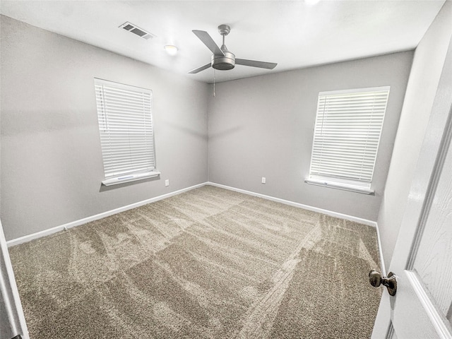 carpeted empty room featuring baseboards, a ceiling fan, and visible vents