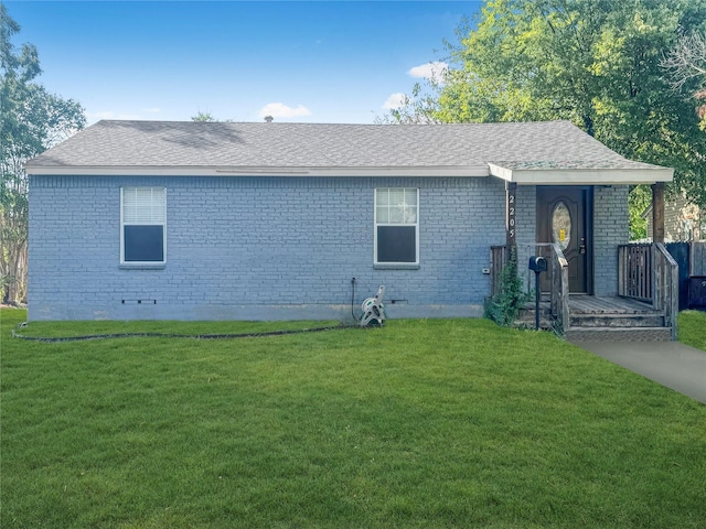 view of front facade with a front yard, roof with shingles, brick siding, and covered porch