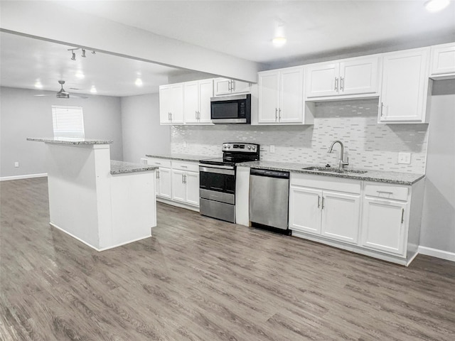 kitchen featuring a sink, stainless steel appliances, white cabinetry, baseboards, and tasteful backsplash