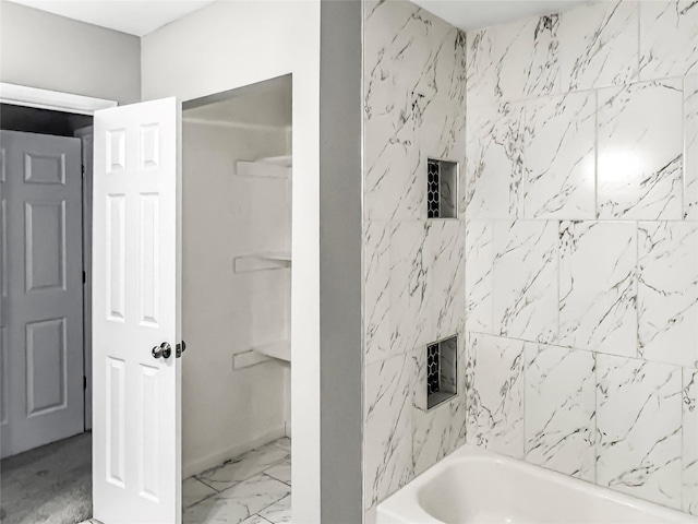 full bath featuring marble finish floor and washtub / shower combination