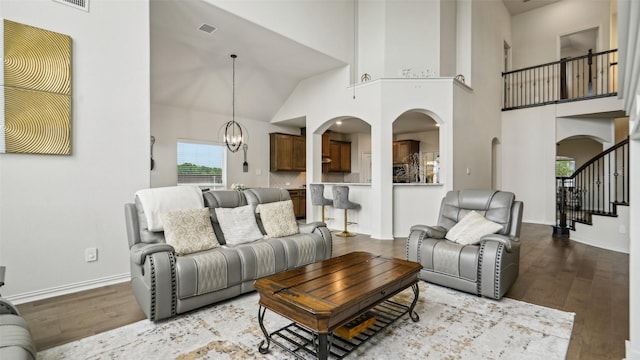 1106 Alaska Dr, Forney, TX 75126 - living area with arched walkways, wood finished floors, a chandelier, a towering ceiling, and stairway