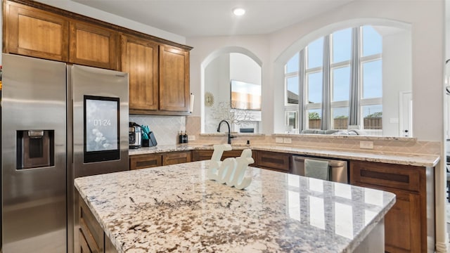 kitchen featuring a sink, light stone countertops, tasteful backsplash, and appliances with stainless steel finishes