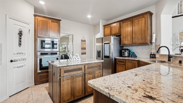 1106 Alaska Dr, Forney, TX 75126 - kitchen featuring stainless steel appliances, a sink, light stone countertops, a center island, and decorative backsplash