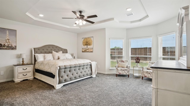 bedroom featuring a tray ceiling, recessed lighting, baseboards, dark colored carpet, and visible vents