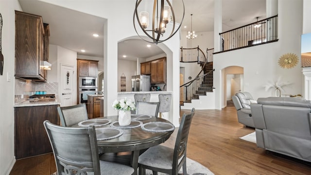 1106 Alaska Dr, Forney, TX 75126 - dining area with arched walkways, stairway, a chandelier, wood finished floors, and recessed lighting