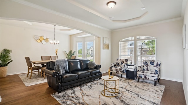 living room featuring wood finished floors, an inviting chandelier, arched walkways, a tray ceiling, and baseboards