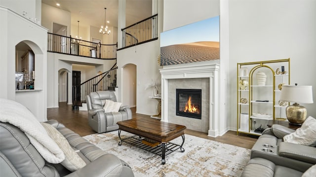 living room with stairs, wood finished floors, arched walkways, a fireplace, and a high ceiling