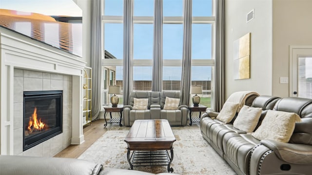living area featuring a healthy amount of sunlight, a fireplace, visible vents, and a towering ceiling