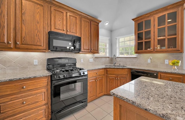 kitchen with a sink, brown cabinetry, light tile patterned flooring, and black appliances