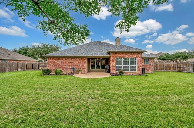 back of property with a yard, a patio area, a fenced backyard, and brick siding
