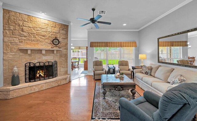 living room featuring ceiling fan, a wealth of natural light, visible vents, and crown molding