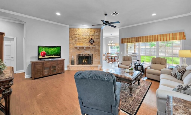 living room featuring ceiling fan with notable chandelier, wood finished floors, ornamental molding, visible vents, and baseboards