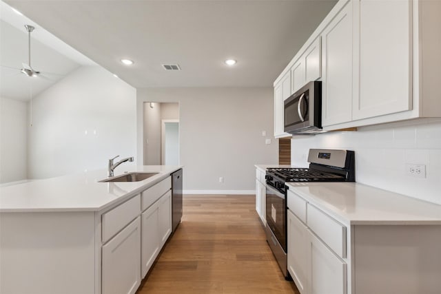 kitchen with a sink, stainless steel appliances, light wood-type flooring, visible vents, and a ceiling fan