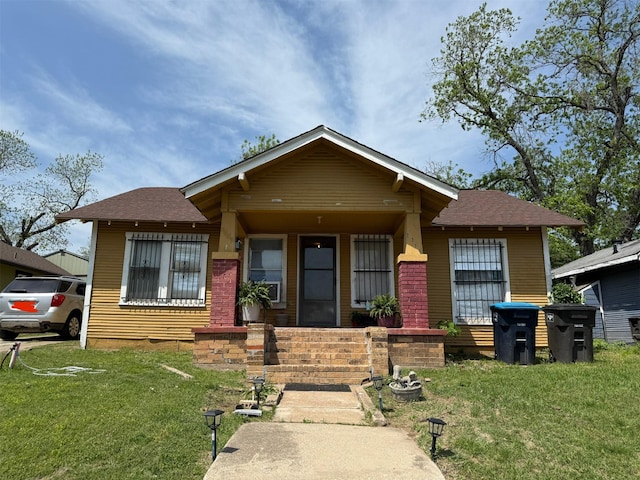 bungalow-style house with roof with shingles and a front lawn