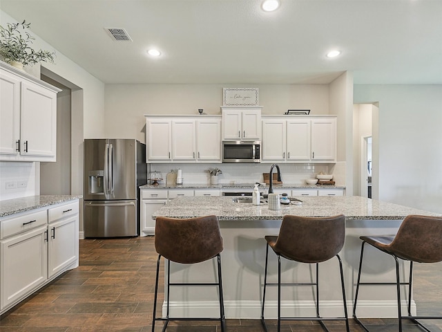 1455 Radecke Rd, Krum, TX 76249 - kitchen with appliances with stainless steel finishes, a sink, white cabinets, a kitchen bar, and dark wood finished floors