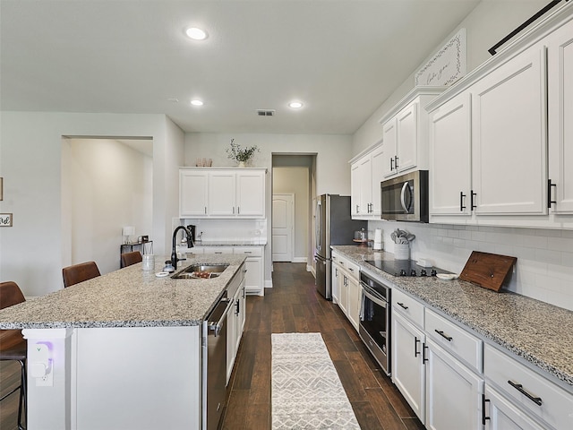 1455 Radecke Rd, Krum, TX 76249 - kitchen featuring a sink, stainless steel appliances, a breakfast bar, white cabinetry, and recessed lighting