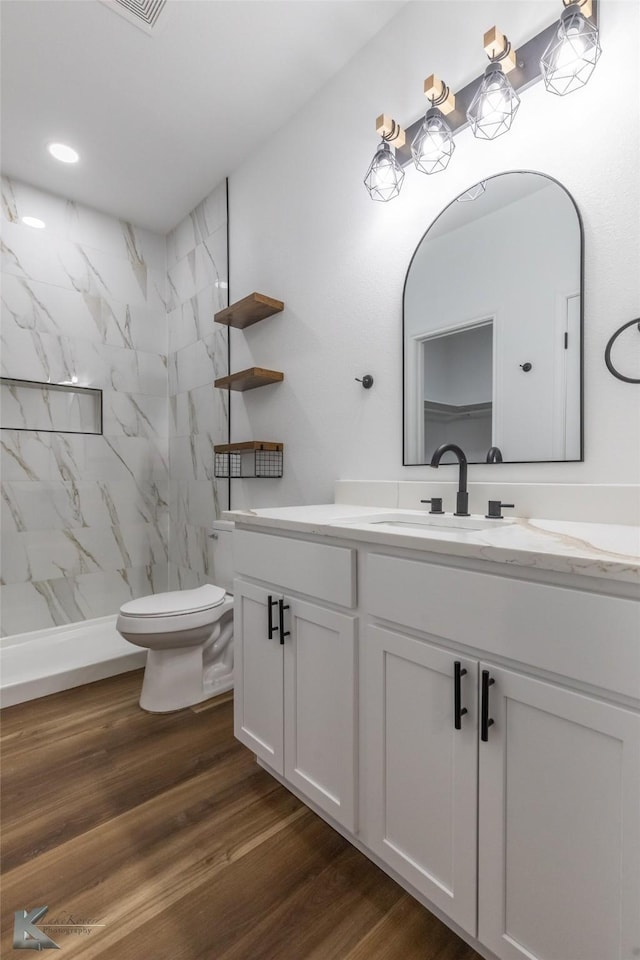 full bathroom with toilet, a marble finish shower, wood finished floors, and vanity