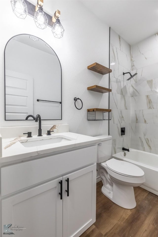 bathroom featuring toilet, shower / bathing tub combination, wood finished floors, and vanity