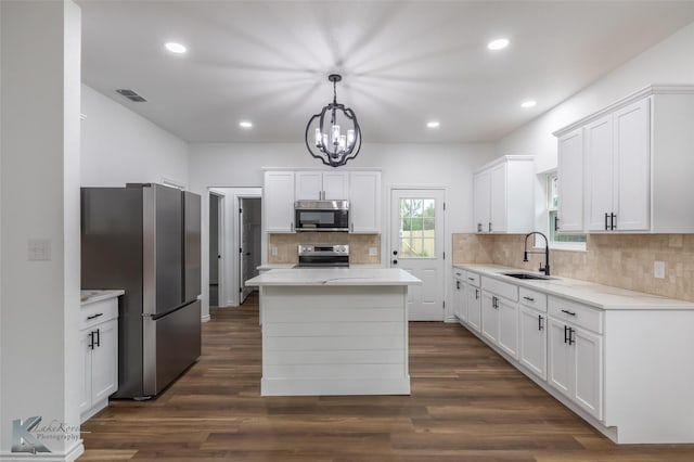 kitchen with a sink, stainless steel appliances, tasteful backsplash, visible vents, and an inviting chandelier