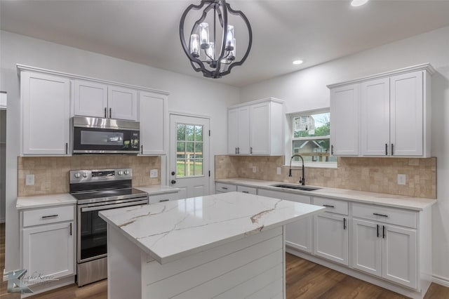 kitchen with a sink, stainless steel appliances, white cabinets, decorative backsplash, and dark wood-style floors