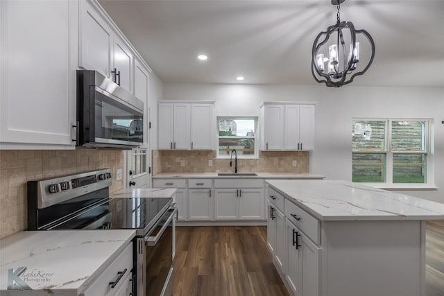 kitchen with a sink, stainless steel appliances, a notable chandelier, white cabinetry, and dark wood-type flooring