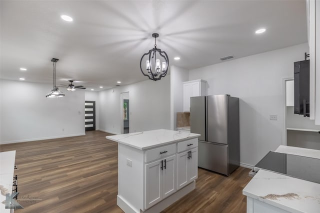 kitchen with ceiling fan with notable chandelier, freestanding refrigerator, visible vents, dark wood finished floors, and white cabinets