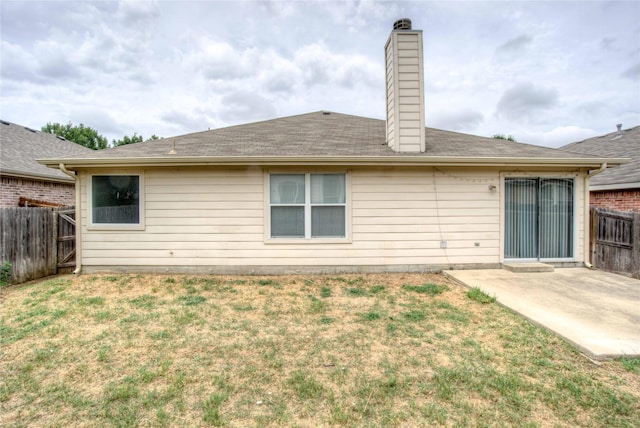 rear view of property featuring a yard, a patio area, fence, and a chimney
