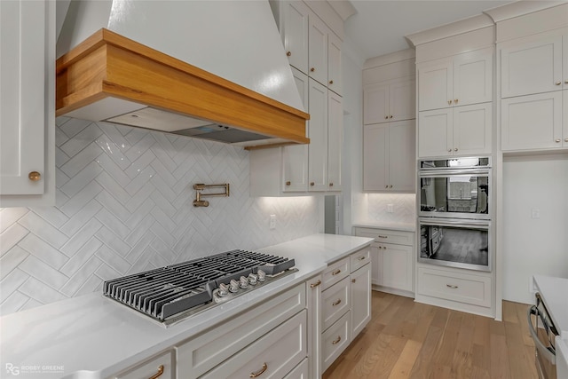 kitchen featuring light countertops, white cabinets, appliances with stainless steel finishes, and decorative backsplash
