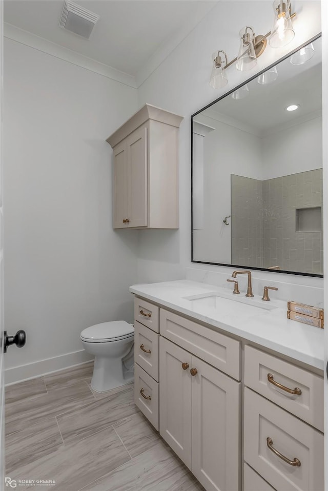 bathroom featuring toilet, crown molding, vanity, and visible vents