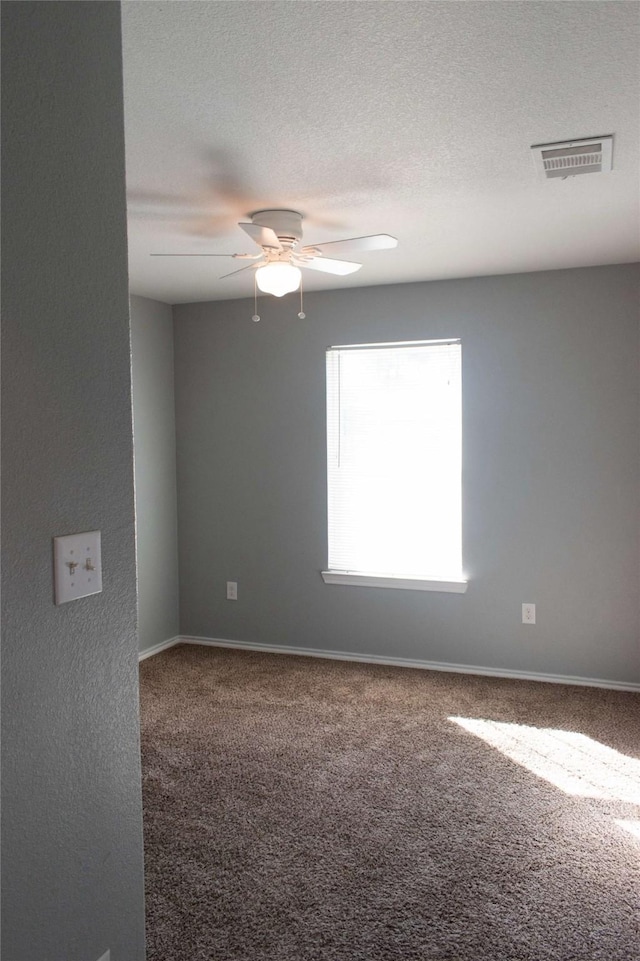 spare room featuring carpet, visible vents, baseboards, and a ceiling fan