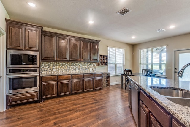3530 Beaumont Dr, Wylie, TX 75098 - kitchen featuring appliances with stainless steel finishes, a sink, dark wood-style flooring, backsplash, and dark brown cabinetry