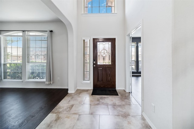 1112 Crest Ridge Dr, Glenn Heights, TX 75154 - entryway featuring baseboards, arched walkways, light wood-style flooring, and a high ceiling
