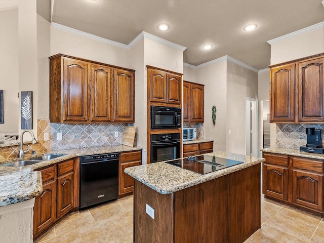 kitchen with a sink, tasteful backsplash, light stone counters, black appliances, and a center island