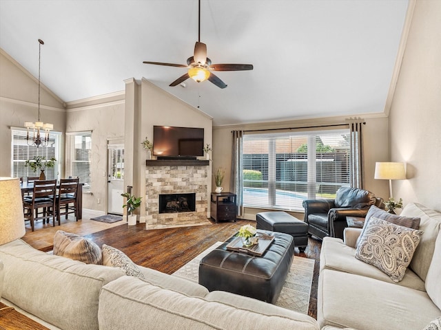 living area with ceiling fan with notable chandelier, wood finished floors, high vaulted ceiling, a fireplace, and crown molding