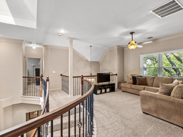 carpeted living area with visible vents, a ceiling fan, and ornamental molding