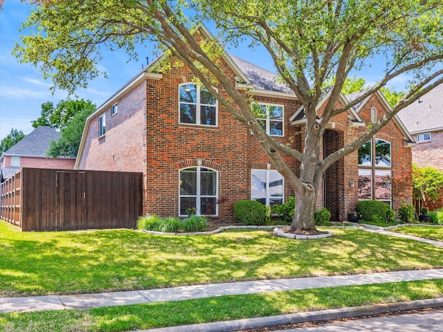 view of front of property with brick siding, fence, and a front yard