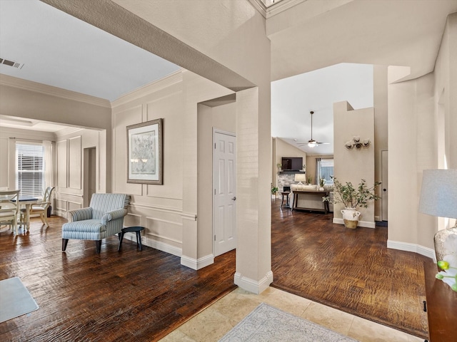 foyer entrance featuring wood finished floors, a ceiling fan, crown molding, visible vents, and a towering ceiling