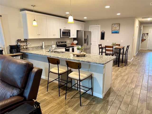 124 Oakwood St, Chico, TX 76431 - kitchen with open floor plan, a peninsula, a kitchen breakfast bar, light wood-style floors, and appliances with stainless steel finishes