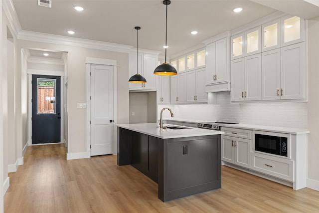 kitchen featuring light wood-type flooring, black microwave, baseboards, and a sink