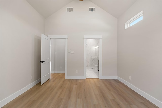 unfurnished bedroom featuring baseboards, light wood-style floors, visible vents, and high vaulted ceiling