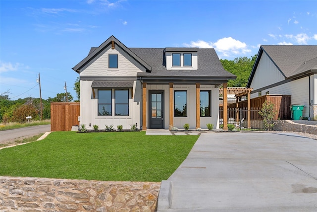view of front of home with board and batten siding, driveway, fence, a shingled roof, and a front yard